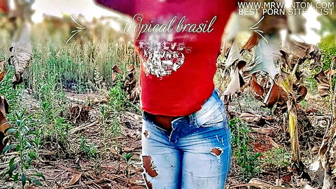 Sexy Brazilian woman in red Tropical Brasil shirt and ripped jeans outdoor tease