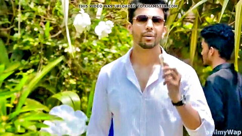 Indian man in open white shirt and sunglasses in jungle, hot outdoor scene