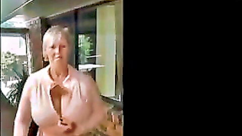 Blonde mature MILF smiles teasing big natural tits cleavage in deeply unbuttoned pink blouse
