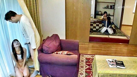 Skinny Japanese teen kneels exposing small tits and shaved pussy to standing man's cock in living room
