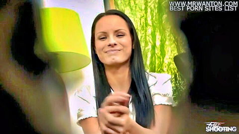 Young brunette smiling teasingly in white blouse during casting interview