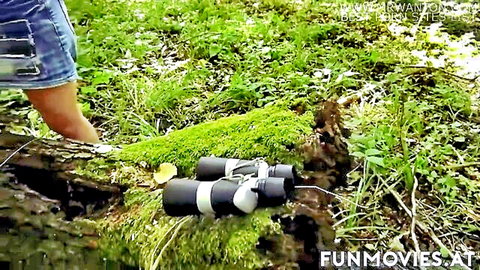 Adrienne Kiss in denim shorts, barefoot outdoors on mossy log with binoculars