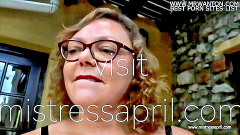 Blonde mature mistress April in glasses smirks seductively for femdom domination