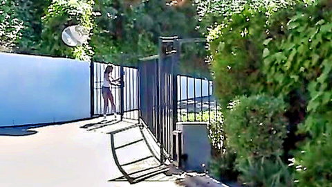 Amateur coed in bikini bending over gate, teasing outdoor view