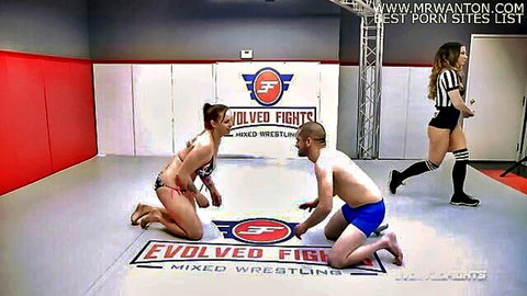 Muscular bald guy pins sexy bikini-clad woman in submission hold during intense mixed wrestling match
