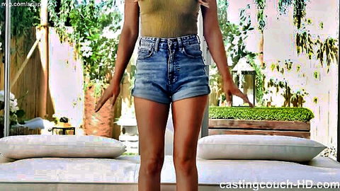 Attractive Latina in denim shorts and green top posing on casting couch