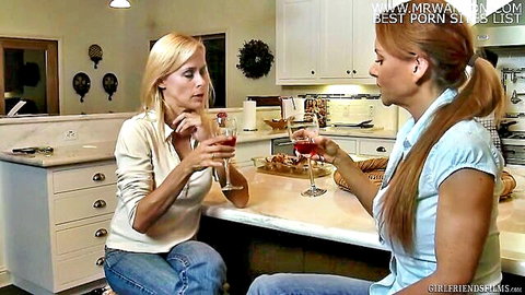 Two women in casual clothes sipping wine, flirty lesbian kitchen moment