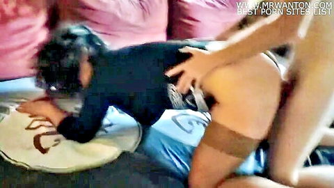 Mature woman in black stockings bent over doggy style as young man grips her bare ass on couch
