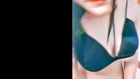 Busty Asian woman in deep green bra showing massive cleavage on webcam