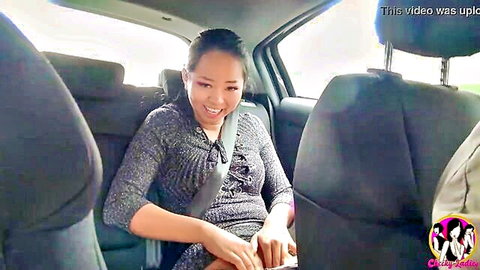 Smiling Asian Jureka in gray dress in car backseat