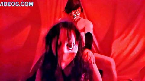 Masked women in nude embrace with intense red lighting