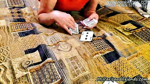 Slim Asian woman in red top plays stripping card game, holding spades