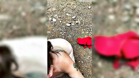 Amateur nude woman lies on sandy ground showing bare pale ass and tattooed back with red flip-flops nearby