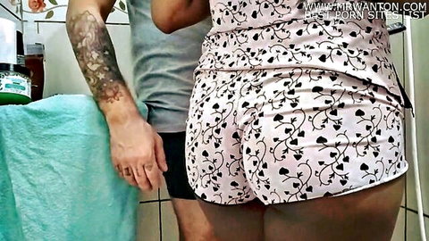 Tattooed guy grabs juicy big ass of woman in tight pink floral shorts from behind in bathroom