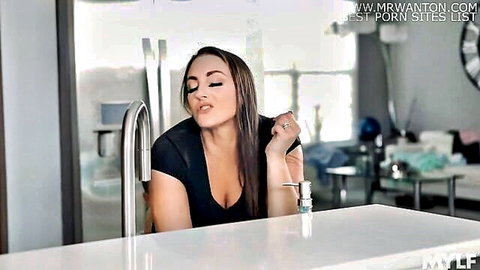 Tattooed MILF puckers lips teasing blowjob pose in kitchen with deep cleavage tits