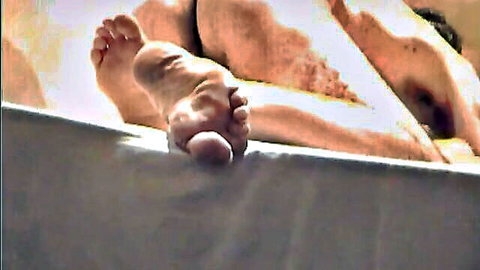 Closeup of hairy man's bare feet soles flexed on bed foot fetish view