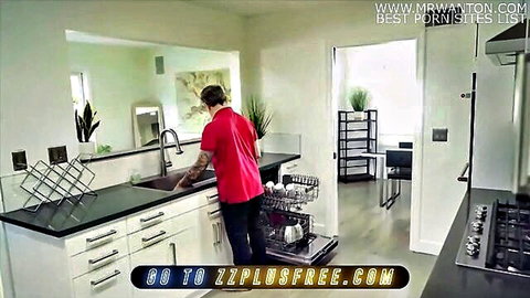 Man in red shirt washing dishes in modern kitchen sink with dishwasher open