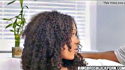 Sexy curly-haired ebony woman smiles in profile as black man's hand rests on her shoulder