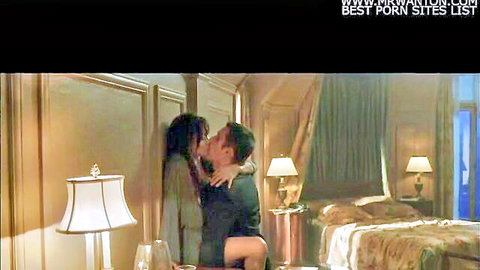 Brunette babe passionately kissing suited guy in luxurious bedroom embrace