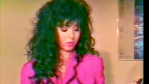 Seductive Asian woman with voluminous curly black hair in pink blazer