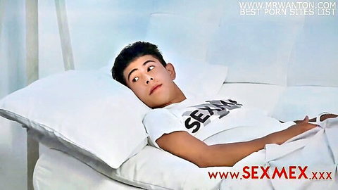 Young Latino guy smirking playfully in bed wearing tight white SEX t-shirt teasing cock bulge