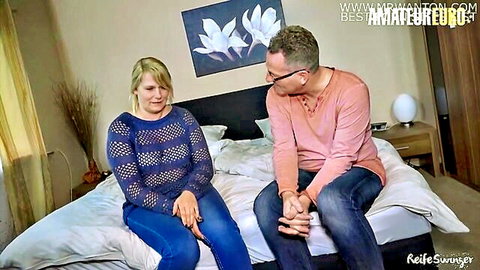 Blonde mature German swinger couple sitting intimately on bed in amateur video