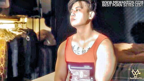 Muscular Asian guy with tattoos in red tank top, intense gaze