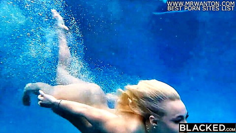 Nude blonde swimmer kicking legs underwater exposing small bare ass in blue pool