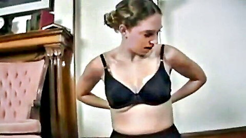 Slim Caucasian woman in black bra, hands behind back, prepping for Sybian orgasms