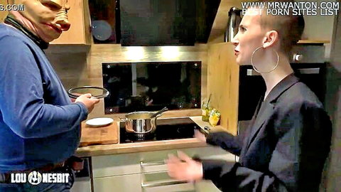 Lia Louise in suit confronts masked Lou Nesbit in kitchen pegging setup