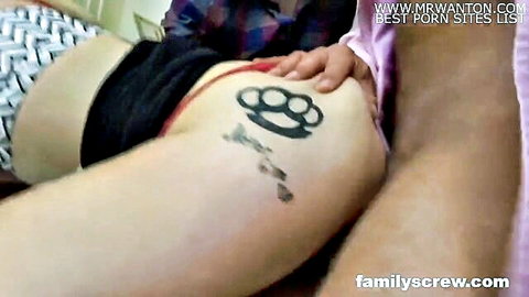 Close-up of woman's thigh with brass knuckles tattoo, man's hand on her leg in shorts