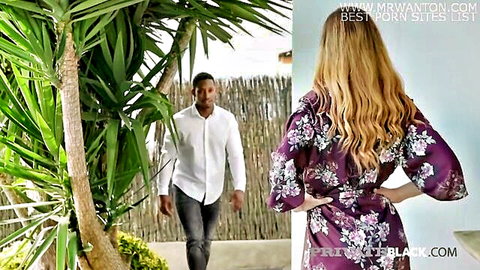 Hot blonde in floral purple robe stands teasingly with black stud approaching from behind outdoors