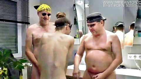 Naked mature Caucasian men surround nude woman in sauna locker room