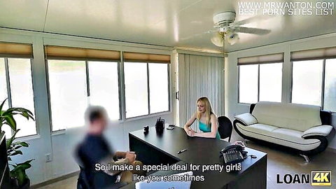 Blonde petite girl in teal top smiles at blurred agent in office loan casting negotiation