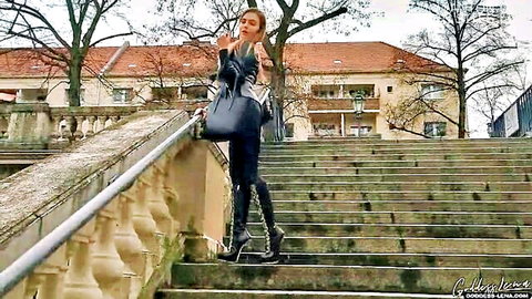 Sexy brunette in tight black pants and knee-high boots smokes seductively on outdoor stairs