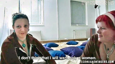 Two Czech women in casual tops chatting intimately on bed