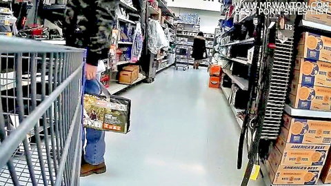 Man in camo jacket pushes shopping cart down store aisle in public supermarket