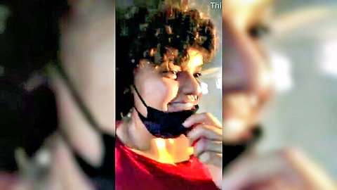 Curly-haired babe pulls down black mask revealing plump lips and smile in tight red top