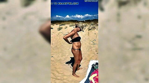 Slim blonde in black bikini posing on beach, stripping tease