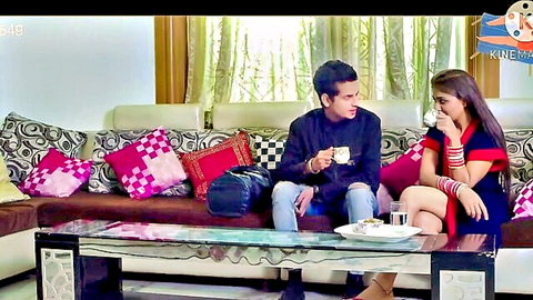 Indian couple flirting intimately on couch sipping tea cups smiling seductively