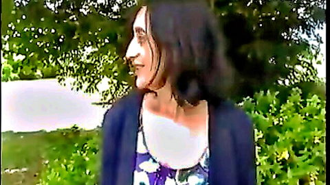 Smiling brunette woman in open cardigan and floral top posing outdoors