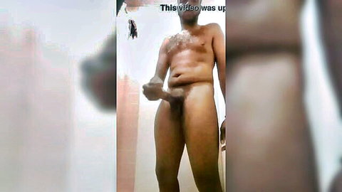 Muscular naked black guy holds his hard cock standing in steamy bathroom with soap suds on chest
