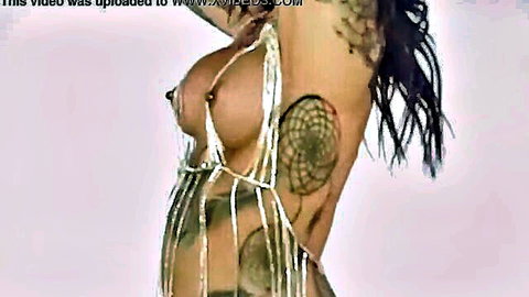 Tattooed brunette Gipsydeb in shiny chain top exposing breasts, seductive side pose