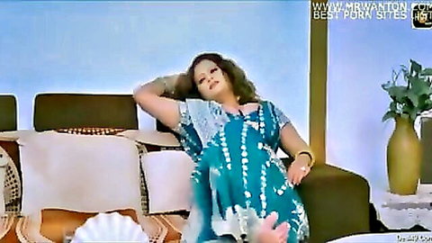 Seductive Indian woman in blue patterned dress posing on couch
