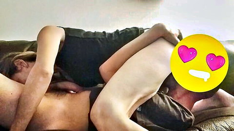 Intimate couple embrace in black top and nude on couch, passionate spooning
