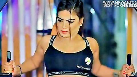 Busty Indian Desi babe in tight black sports bra posing with pink dumbbells in gym