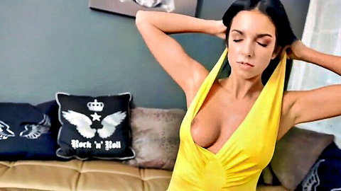 Foxxi Black posing seductively in low-cut yellow dress, showing cleavage