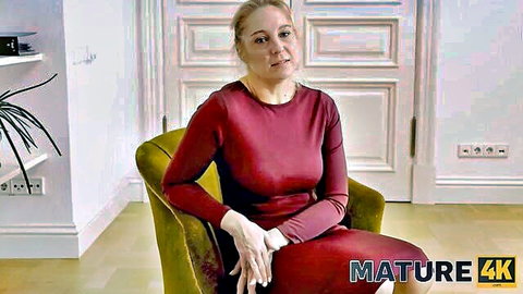 Mature blonde woman in red dress and stockings during interview