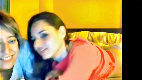 Two smiling girls cuddling intimately on bed, playful lesbian vibe