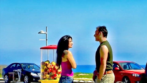Curvy brunette in pink top flirts with muscular guy on sunny beach